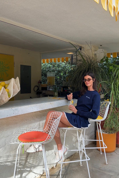 Woman sitting in a navy sweatshirt at a summer bar